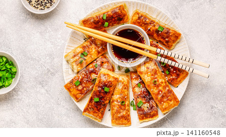 Dumplings are arranged on a plate with a small bowl of dipping sauce Dumplings are arranged on a plate with a small bowl of dipping sauce 141160548