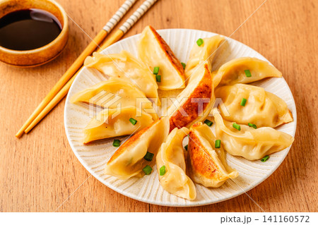 Dumplings served on a plate with green onions 141160572