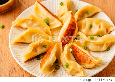 Dumplings served on a plate with green onions 141160573