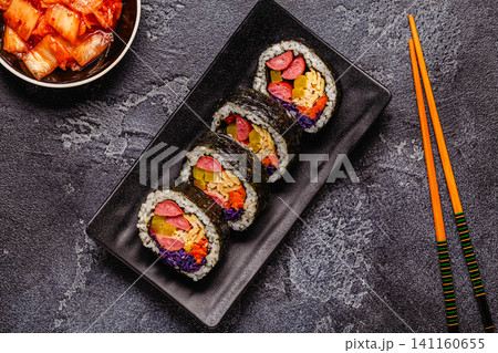 A black plate filled with kimbap (or gimbap) that have colorful fillings. A black plate filled with kimbap (or gimbap) that have colorful fillings. 141160655