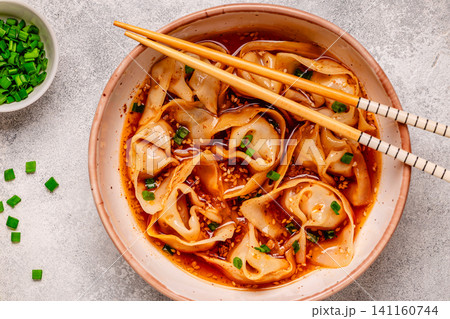 Wontons are placed in a bowl with spicy sauce. 141160744