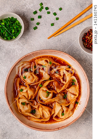 Wontons are placed in a bowl with spicy sauce. 141160745