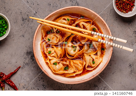 Wontons are placed in a bowl with spicy sauce. Wontons are placed in a bowl with spicy sauce. 141160746