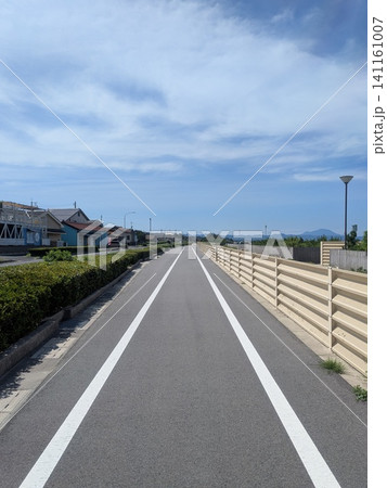 青空の下にまっすぐ伸びるサイクリングロードと遊歩道 141161007