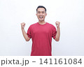Man smiles broadly, fists raised in victory. He wears a simple red t-shirt. White background offers clean, focused presentation. His expression shows pure excitement and joy. Perfect for celebration 141161084