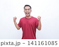 Man smiles broadly, fists raised in victory. He wears a simple red t-shirt. White background offers clean, focused presentation. His expression shows pure excitement and joy. Perfect for celebration 141161085