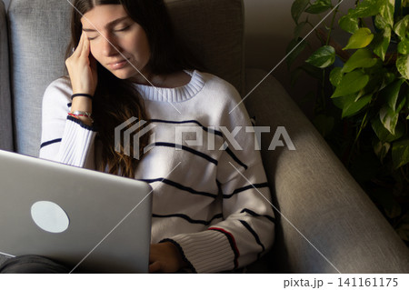 Young woman working remotely from home, attending a virtual meeting feeling stressed, tired, and frustrated Young woman working remotely from home, attending a virtual meeting feeling stressed, tired, and frustrated 141161175