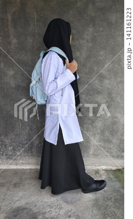 Muslim High School Student with Backpack Walking Against Concrete Wall Muslim High School Student with Backpack Walking Against Concrete Wall 141161223