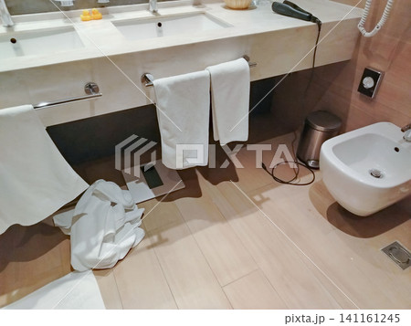 Modern bathroom interior featuring white towels hanging on a sink, a bidet, and a waste bin on a wooden floor with a clean, minimalist design Modern bathroom interior featuring white towels hanging on a sink, a bidet, and a waste bin on a wooden floor with a clean, minimalist design 141161245