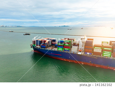 Aerial view of container cargo ship at sea. International shipping and logistics. Maritime freight transportation. Global trade and export import industry. Commercial vessel carrying containers. Aerial view of container cargo ship at sea. International shipping and logistics. Maritime freight transportation. Global trade and export import industry. Commercial vessel carrying containers. 141162102