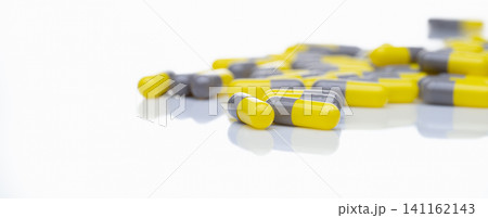 Yellow and gray probiotic capsule pill on white background. Probiotic supplement. Gut health. Dietary supplements. Probiotics for a healthy gut. Lactobacillus acidophilus and Bifidobacterium animalis. 141162143