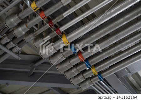 Electrical conduit system and tube of electric cable installed on building ceiling. Industrial infrastructure. Efficient electrical wiring installation and management. Wiring and conduit system. 141162164