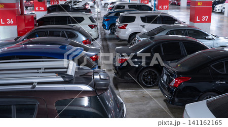 Busy underground car parking lot. Organized rows of vehicles in an urban hub. Urban convenience. Crowded parking space underground of the exhibition and convention center. Indoor car parking lot. Busy underground car parking lot. Organized rows of vehicles in an urban hub. Urban convenience. Crowded parking space underground of the exhibition and convention center. Indoor car parking lot. 141162165