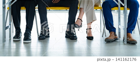 Unrecognizable business professionals sitting in a waiting room before a job interview or corporate meeting. Recruitment, diversity, workplace culture, patience, and modern office. Office appointment. Unrecognizable business professionals sitting in a waiting room before a job interview or corporate meeting. Recruitment, diversity, workplace culture, patience, and modern office. Office appointment. 141162176