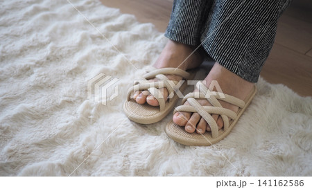 Feet in sandals on a soft rug indoors Feet in sandals on a soft rug indoors 141162586