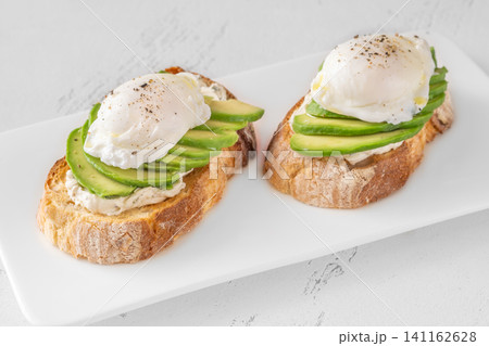 Avocado toast with poached eggs on artisan bread plate Avocado toast with poached eggs on artisan bread plate 141162628