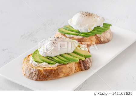 Avocado toast with poached eggs on artisan bread plate Avocado toast with poached eggs on artisan bread plate 141162629