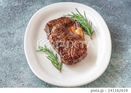 Perfectly grilled beef steak with rosemary on white plate premium restaurant presentation Perfectly grilled beef steak with rosemary on white plate premium restaurant presentation 141162639