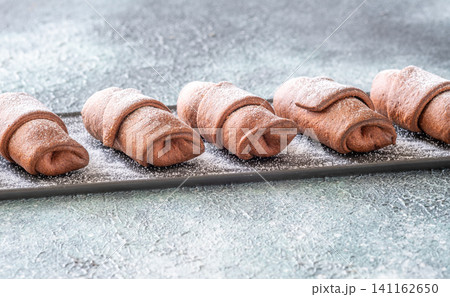 Chocolate croissants dusted with sugar on slate platter bakery top view composition Chocolate croissants dusted with sugar on slate platter bakery top view composition 141162650