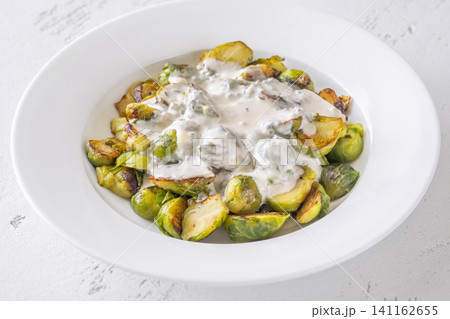 Roasted Brussels sprouts with creamy blue cheese sauce in white bowl Roasted Brussels sprouts with creamy blue cheese sauce in white bowl 141162655