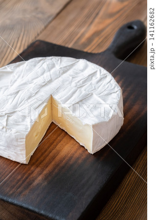 Creamy Camembert Cheese Wheel With Slice Removed On Rustic Wooden Board Display Creamy Camembert Cheese Wheel With Slice Removed On Rustic Wooden Board Display 141162682