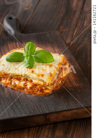 Traditional Lasagna Bolognese Slice Served On Dark Rustic Wooden Board Traditional Lasagna Bolognese Slice Served On Dark Rustic Wooden Board 141162721