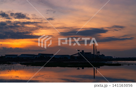 Landscape of factory industry buildings with dark blue and orange sunset sky reflection on water in the river. Warehouse building at night. Clean environment around factory. Factory closed. Landscape of factory industry buildings with dark blue and orange sunset sky reflection on water in the river. Warehouse building at night. Clean environment around factory. Factory closed. 141163056