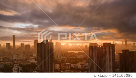 Cityscape with skyscraper building and morning sunlight. Riverfront city with orange sunrise. Urban modern building. Crowded with apartment building. Urban skyline. Capital city. Residential building. 141163086