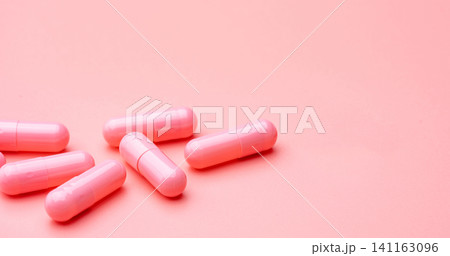 Pink capsules pill on pink background. Vitamins and supplements. Online pharmacy. Pharmacy store banner. Pharmaceutical industry. Woman's health insurance concept. Pills for love and happy life. Pink capsules pill on pink background. Vitamins and supplements. Online pharmacy. Pharmacy store banner. Pharmaceutical industry. Woman's health insurance concept. Pills for love and happy life. 141163096