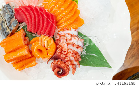 Japanese food combo set. Salmon, tuna sashimi, giant octopus and Crab sticks serve with crushed ice in white plate on restaurant table. Fish meat sliced. Seafood buffet. Healthy Japanese food. Japanese food combo set. Salmon, tuna sashimi, giant octopus and Crab sticks serve with crushed ice in white plate on restaurant table. Fish meat sliced. Seafood buffet. Healthy Japanese food. 141163189