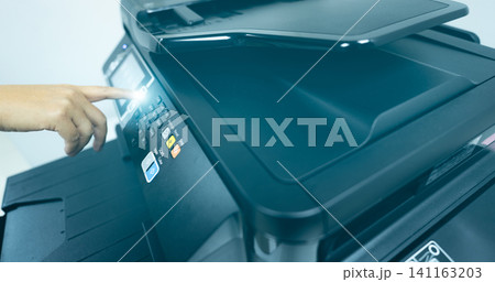 Office worker hand press button on multifunction laser printer. Copy, print, scan, and fax machine in office. Modern print technology. Photocopy machine. Document and paper work concept. Scanner. Office worker hand press button on multifunction laser printer. Copy, print, scan, and fax machine in office. Modern print technology. Photocopy machine. Document and paper work concept. Scanner. 141163203