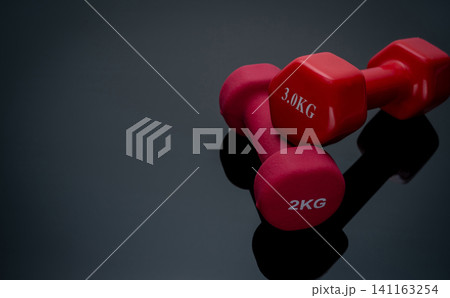 Red dumbbells isolated on black background. 2 and 3 kg dumbbells. Weight training equipment. Bodybuilding workout accessories. Healthy lifestyle concept. Anaerobic exercise. Bodybuilding sports. Red dumbbells isolated on black background. 2 and 3 kg dumbbells. Weight training equipment. Bodybuilding workout accessories. Healthy lifestyle concept. Anaerobic exercise. Bodybuilding sports. 141163254