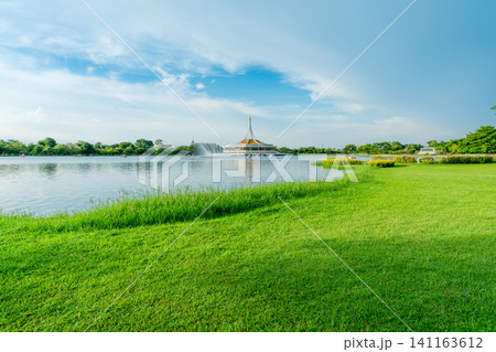 Lake and green grass field at the park. Watercycle in lake near pavilion. Lawn and garden in the park on summer. Green tree and grass field. Picnic on holiday. People relax and have activity in park. Lake and green grass field at the park. Watercycle in lake near pavilion. Lawn and garden in the park on summer. Green tree and grass field. Picnic on holiday. People relax and have activity in park. 141163612