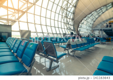 Blurred seat in departure lounge at airport terminal. Distance for one seat keep distance to protect coronavirus and passenger social distancing for safety. Glass window with geometric architecture. Blurred seat in departure lounge at airport terminal. Distance for one seat keep distance to protect coronavirus and passenger social distancing for safety. Glass window with geometric architecture. 141163643