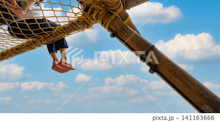 Summer travel at the beach with blue sky and white clouds. Summer vibes. Summer vacations. Relax on vacations. Woman with pink flipflop sit on net rope with enjoy and relax mood on holiday at resort. Summer travel at the beach with blue sky and white clouds. Summer vibes. Summer vacations. Relax on vacations. Woman with pink flipflop sit on net rope with enjoy and relax mood on holiday at resort. 141163666