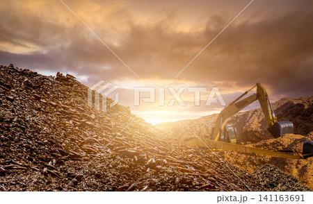 Blur photo of pile of brown glass bottle for recycle and backhoe on wood chips pile. Recycle materials. Paper industry. Glass bottle waste for recycle. Sustainable resources. Bulldozer working. Blur photo of pile of brown glass bottle for recycle and backhoe on wood chips pile. Recycle materials. Paper industry. Glass bottle waste for recycle. Sustainable resources. Bulldozer working. 141163691