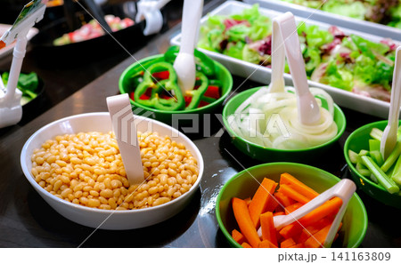 Salad bar buffet at restaurant. Fresh salad bar buffet for lunch or dinner. Healthy food. Beans and orange carrots in white and green bowl on counter. Catering food. Banquet service. Vegetarian food. 141163809