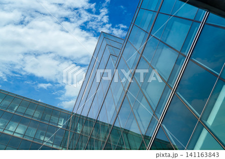 Low angle view of modern glass office building abstract background. Exterior office glass building architecture. Company glass window. Skyscraper corporate building. Financial business center tower. Low angle view of modern glass office building abstract background. Exterior office glass building architecture. Company glass window. Skyscraper corporate building. Financial business center tower. 141163843