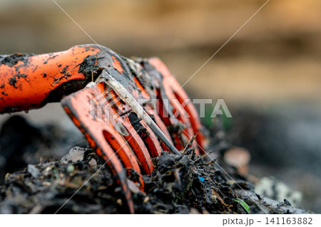 Closeup orange rake on pile of dirty plastic waste on blurred background. Beach environmental pollution concept Clean up rubbish on beach. Ocean garbage. Coast polluted. Closeup orange rake on pile of dirty plastic waste on blurred background. Beach environmental pollution concept Clean up rubbish on beach. Ocean garbage. Coast polluted. 141163882
