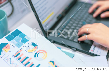 Sale report and business financial graph chart on blur office worker hand typing on the laptop at the computer desk. Paperwork from an accountant. Document work. Corporate financial analysis. Sale report and business financial graph chart on blur office worker hand typing on the laptop at the computer desk. Paperwork from an accountant. Document work. Corporate financial analysis. 141163913