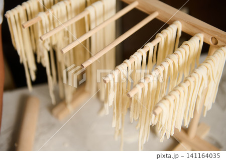 Homemade pasta noodles drying on wooden rack in kitchen for fresh Italian cooking Homemade pasta noodles drying on wooden rack in kitchen for fresh Italian cooking 141164035