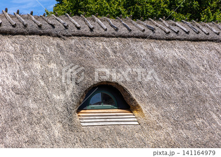 Traditional thatched roof with small arched window Traditional thatched roof with small arched window 141164979