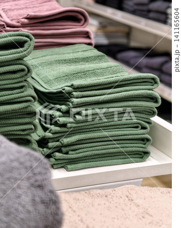 Green towels neatly stacked on counter in home goods supermarket Green towels neatly stacked on counter in home goods supermarket 141165604