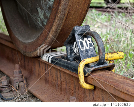 Freight wagon wheel locked on industrial railroad with steel brake chock for safety Freight wagon wheel locked on industrial railroad with steel brake chock for safety 141165629