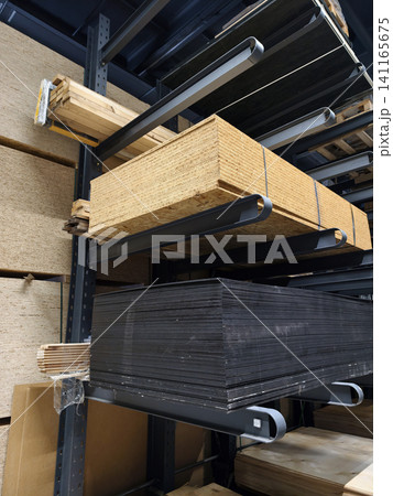 Stacked wood materials such as OSB sheets MDF boards particle boards and slats are organized on high capacity warehouse shelving in a timber storage area Stacked wood materials such as OSB sheets MDF boards particle boards and slats are organized on high capacity warehouse shelving in a timber storage area 141165675