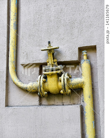 Gas shut off installation positioned on an outer residential wall with yellow utility pipe, illustrating a functional engineering solution for domestic gas networks Gas shut off installation positioned on an outer residential wall with yellow utility pipe, illustrating a functional engineering solution for domestic gas networks 141165679