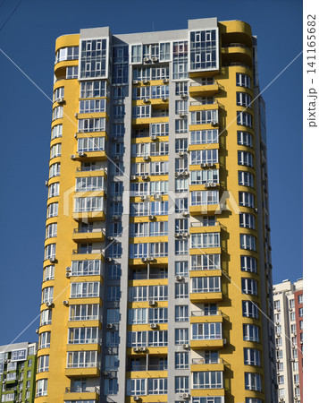 Modern housing towers with colorful facades rising against vivid blue atmospheric sky Modern housing towers with colorful facades rising against vivid blue atmospheric sky 141165682