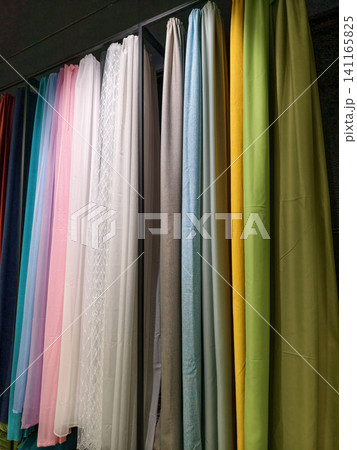 Bright, multicolored curtains arranged on display for customers inside a shop 141165825