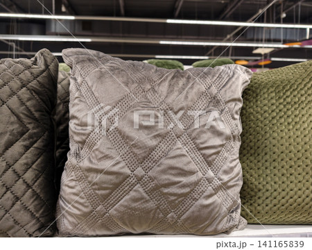 Decorative cushions neatly arranged on store shelves highlighting home furnishing products available in supermarket retail environment Decorative cushions neatly arranged on store shelves highlighting home furnishing products available in supermarket retail environment 141165839