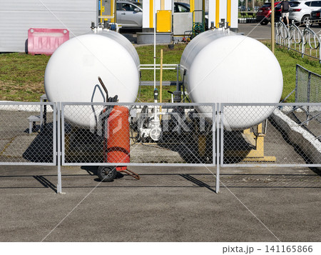 Two butane fuel tanks with industrial safety equipment at a public gas station used for fuel storage and distribution operations Two butane fuel tanks with industrial safety equipment at a public gas station used for fuel storage and distribution operations 141165866